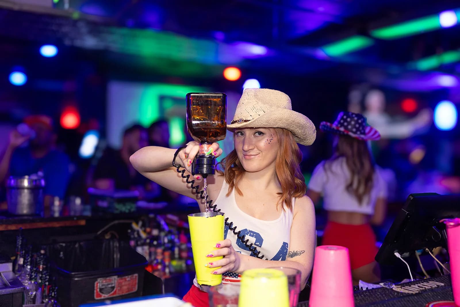 A Wacko's team member pouring a drink behind the glowing bar